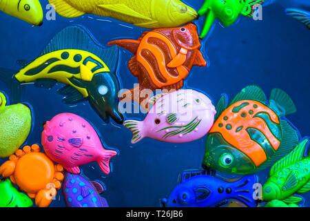 Mehrere igushek in Form von marine Fische schwimmen im Wasser. Die Spielzeuge sind sehr helle Farben und schönen vor dem Hintergrund des blauen Wassers. Stockfoto