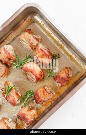 Gebratenes Schweinefilet im Speckmantel gewickelt und gebacken mit Weißwein in einen Bräter. Stockfoto