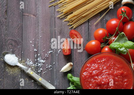 Italienische Tomatensauce weiß Basilikum und Vollkornnudeln auf hölzernen Hintergrund Stockfoto