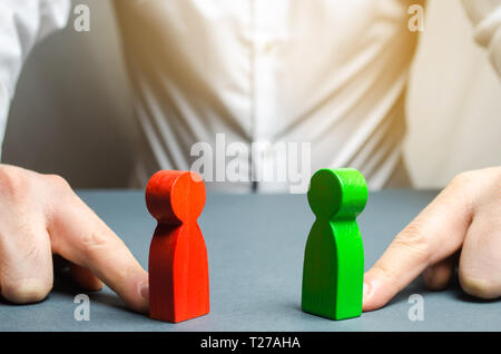 Der Mann drückt den roten und grünen Zahlen zu einander. Die Suche nach einem Kompromiss, Mediation in Verhandlungen. Spinnen Intrigen. Interessenkonflikt, Stockfoto