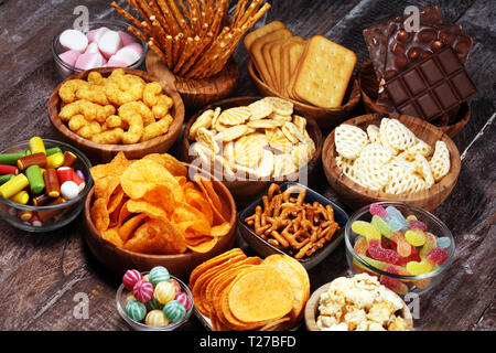 Salzige Snacks. Brezeln, Chips, Kekse in hölzernen Schüsseln. Ungesunde Produkte. Essen schlecht für Abbildung, Haut, Herz und Zähne. Sortiment von schnellen carbohydra Stockfoto