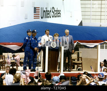 Präsident Ronald Reagan spricht mit einer Masse von mehr als 45.000 Menschen bei der NASA Dryden Flight Research Center nach der Landung von STS-4 am 4. Juli 1982. Auf der rechten Seite des Präsidenten sind Frau Reagan und NASA-Administrator James M. Beggs. Auf der linken Seite sind STS-4 Columbia Astronauten Thomas K. Mattingly und Henry W. Hartsfield, Jr. Prototyp Space Shuttle Enterprise ist im Hintergrund. Stockfoto