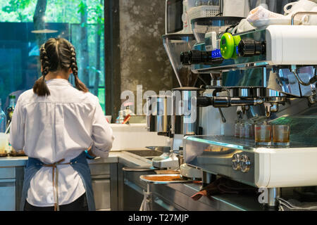 Barista mit einer Kaffeemaschine und bereitet die Tasse Kaffee für einen Kunden Stockfoto