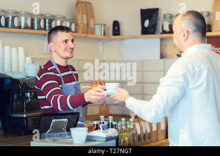 Barista, Tasse Kaffee an den Kunden am Schalter in kleinen Coffee Shop Stockfoto