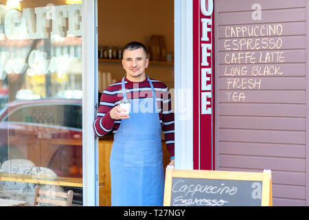 Portrait von Small Business Coffee Shop Besitzer lächelnd und stand vor der Shop serviert Kaffee zum Mitnehmen Stockfoto