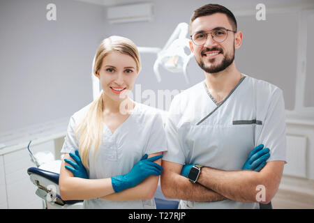 Zwei junge Zahnarzt Fachleute in der Zahnheilkunde. Sie stellen auf Kameras und Lächeln. Die Menschen halten die Hände gekreuzt. Stockfoto