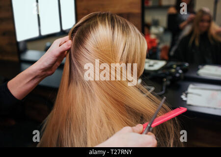 Hairstylist Hände kämmen blondes Haar vor Haarpflege Verfahren im Beauty Salon Stockfoto