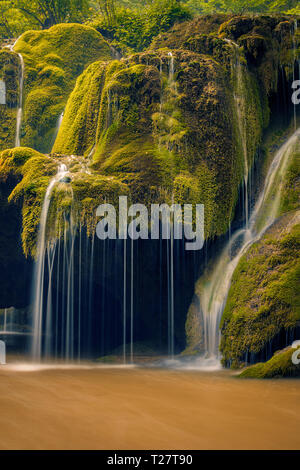 Schönes Detail an einem Wasserfall fließen auf ein Moos bedeckt Rock mit einer Höhle unterhalb in Rumänien mit einer langen Belichtungszeit Stockfoto