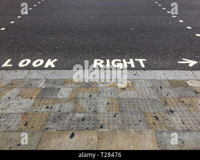 Suchen Sie passende Warnung gemalt auf einem Fußgängerüberweg in London, England, UK Stockfoto