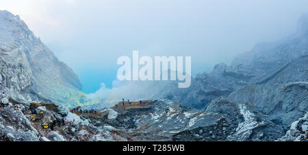 Blick auf den Kawah Ijen Kratersee vulkanischen See mit Touristen und Schwefel Schwefelsäure Bergleute und giftige Gase, die sich aus der Unterseite. Java, Indonesien. Stockfoto