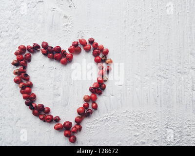 Eine Form von ein Herz aus Holz rosa Pfefferkörner auf weißem Hintergrund. Mit Platz für Kopieren. Valentines Tag. Stockfoto