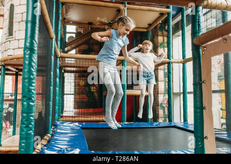 Zwei lustige Mädchen springen auf dem Trampolin, Kinder Game Center. Aufgeregt childs Spaß auf dem Spielplatz im Freien. Kinder spielen in Amusement Center Stockfoto
