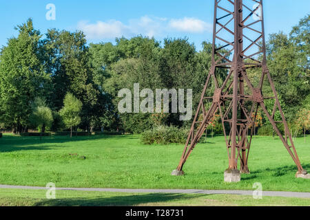 Rostiges Metall Unterstützung der Hochspannungsleitung, stehend auf der Wiese im Stadtpark. Stockfoto