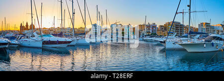 Das abendliche Panorama von Msida Port von der Promenade der Pieta, mit Blick auf die Wohnviertel, St. Joseph Parish Church und hellen Sonnenuntergang, Ma Stockfoto