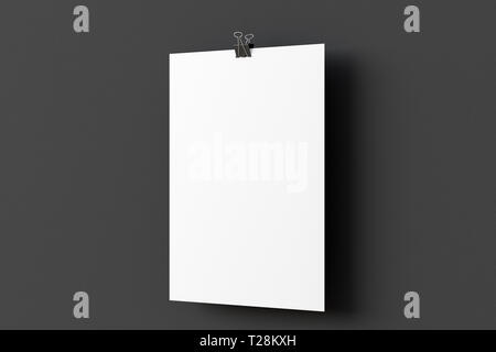 Leeres Poster aus Papier, das an einem Binderclip auf schwarzem Wandhintergrund hängt Stockfoto