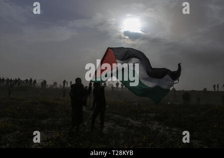 Die Demonstranten schwenkten gesehen eine riesige Flagge bei Zusammenstößen. Palästinensische Demonstranten der israelischen Armee im Zuge einer Millionen starken Protest auf dem Boden zusammengestoßen, fordern das Recht auf Rückkehr in ihre Heimat an der Grenze zwischen Israel und Gaza im Khan Yunis im südlichen Gazastreifen. Das Gesundheitsministerium in der Hamas-run-Sektor drei Palästinenser durch israelische Feuer während der Auseinandersetzungen getötet wurden. Stockfoto