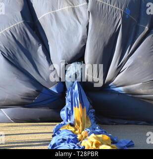 Mann in Jeans in einem Heißluftballon Kriechen nach oben, um sie zu verpacken. Ballon spektakuläre Festival war in Canberra statt. Stockfoto