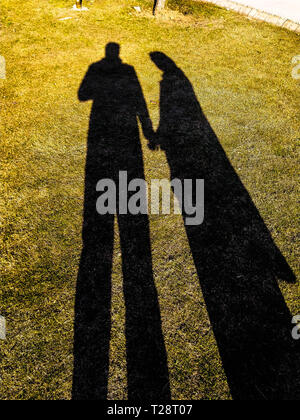Schatten von Mann und Frau in Liebe Hände halten in einem Garten.