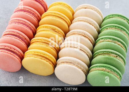 Reihen von verschiedenen bunten französische Macarons auf grauem Hintergrund. Stockfoto