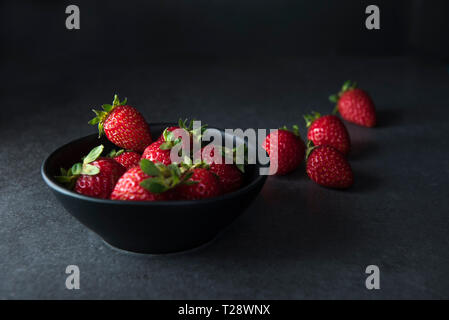 Erdbeeren in dunklen Schüssel auf dunklem Hintergrund mit Kopie Raum, Low-key-Bild Stockfoto