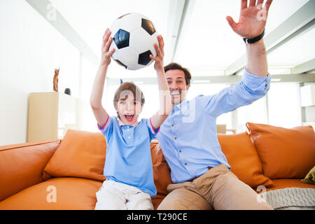 Portrait von Happy Boy watching soccer Match mit Vater auf dem Sofa zu Hause Stockfoto