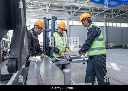 Team von drei Arbeitern in CNC-Fabrik arbeiten an Maschine Stockfoto