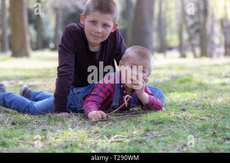 Zwei kleine blonde Brüder im Gras im Frühling Stockfoto