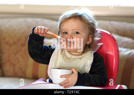 Baby Mädchen, das sich die Fütterung mit Schokolade auf Ihrem Gesicht Stockfoto