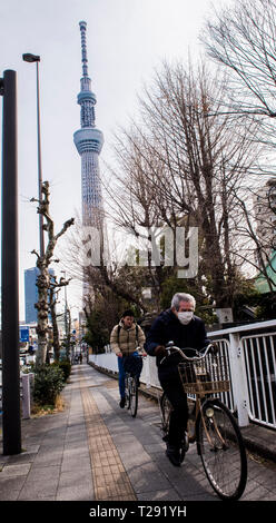 Zwei Männer auf dem Fahrrad entlang der Bürgersteig, Skytree Turm im Hintergrund, Asakusa, Tokyo Stockfoto