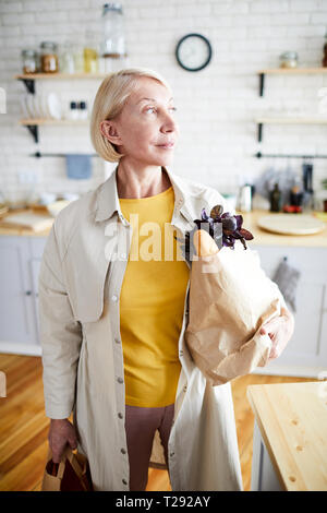 Dame mit vollen Taschen in der Küche Stockfoto