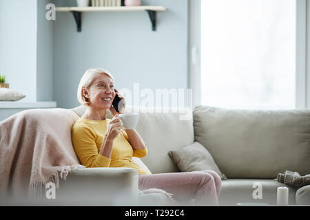Positive Frau trinkt Kaffee zu Hause Stockfoto