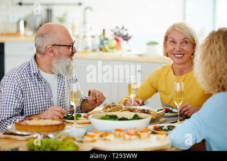 Gerne reif Freunde beim Abendessen zusammen Stockfoto