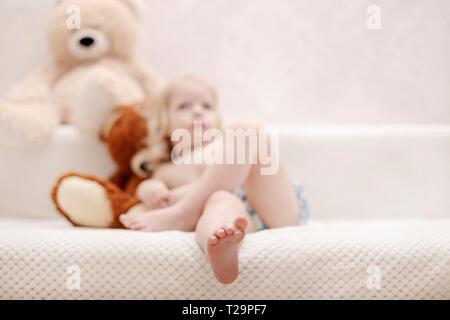 Kleiner Junge, drei Jahre alt, spielt und isst einen Apfel auf dem Sofa. Selektive konzentrieren. Stockfoto