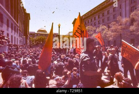 Während der 1971 Tag der Proteste gegen den Vietnamkrieg, eine Masse von männlichen und weiblichen Demonstranten sitzen zusammen an einem sonnigen Tag, am 10. ST NW, zwischen dem US-Justizministerium Gebäude (jetzt die Robert F. Kennedy Justizministerium Gebäude) und der Internal Revenue Service Gebäude, mit der goldenen Kuppel des Smithsonian National Museum of Natural History im Hintergrund sichtbar, in Washington, DC, Mai 1971. () Stockfoto