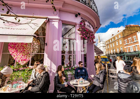 Menschen, die außerhalb von Peggy Porschen Cakes in Belgravia sitzen, einem Konditorei, das für sein markantes pastellrosa Äußere bekannt ist, London, Großbritannien Stockfoto