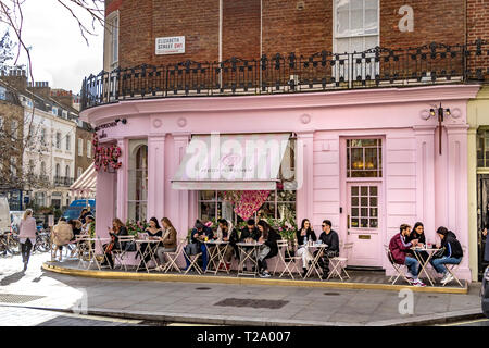 Menschen, die außerhalb von Peggy Porschen Cakes in Belgravia sitzen, einem Konditorei, das für sein markantes pastellrosa Äußere bekannt ist, London, Großbritannien Stockfoto