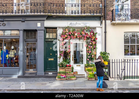 Eine Frau, die vor dem Geschäft für Blumenkunst von Moyses Stevens in Belgravia, London, Großbritannien, steht Stockfoto
