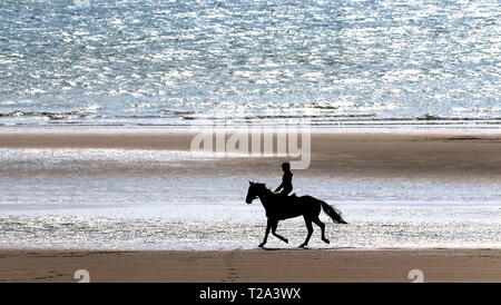Eine Reiterin genießt eine Fahrt am Strand im Camber, Sussex, die kälteren Temperaturen in den kommenden Tagen prognostiziert. Stockfoto