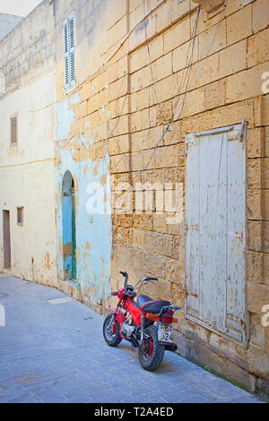 Rotes Motorrad neben der alten Wand Stockfoto