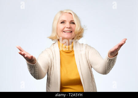 Ältere blonde Frau in Freizeitkleidung begrüssen Ihre Gäste. Positive facial Emotion. Stockfoto