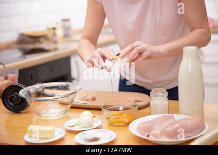Nahaufnahme von einem Paar Hände rissen ein Ei in eine Glasschüssel. Kochen Stockfoto