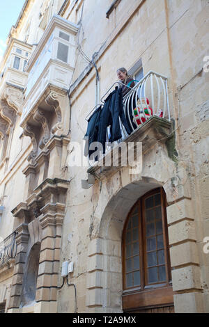 Frau trocknet Wäsche auf ihrem Balkon Stockfoto