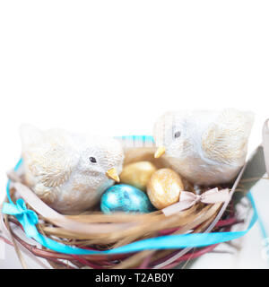 Zwei niedliche handgefertigte kleine Ostern Vögel und deren goldene Eier im Nest, Elternschaft, Adoption, Care Concept. Auf weißem Hintergrund, kopieren Raum f Stockfoto