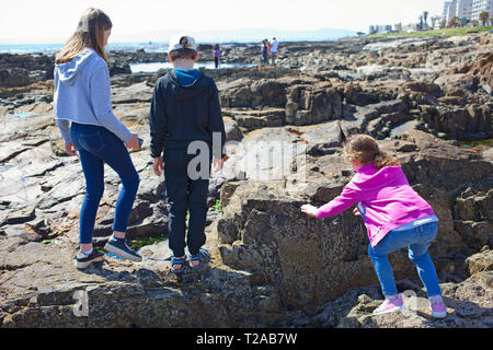 Drei Kinder spielen von Rock Pools, Mouille Point Promenade, Sea Point. Stockfoto