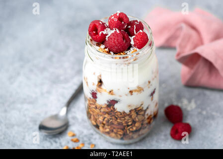 Müsli, Joghurt und Beeren in den jar auf konkrete Tabelle Hintergrund. Detailansicht, selektive konzentrieren. Leckeres Frühstück Parfait mit griechischem Joghurt und knackig Stockfoto