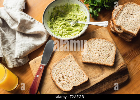 Sandwich Brot und Guacamole auf hölzernen Tisch. Frühstück im Morgenlicht. Gesunde vegetarische Kost Stockfoto