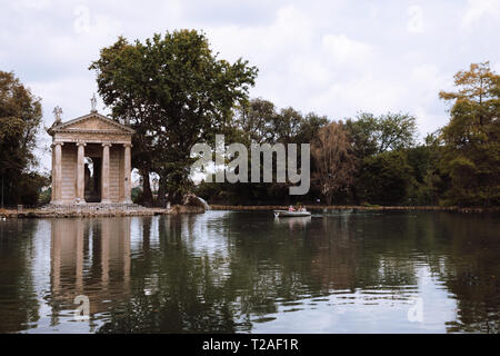 Panoramablick auf den Tempel des Asklepios (Tempio di Esculapio) und See in den öffentlichen Park der Villa Borghese. Tag Sommer und blauer Himmel Stockfoto