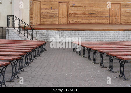 Foto von Bänken, die in der Zukunft liegt. Bänke aus Holz bestehen, sind sie Braun. Im Hintergrund der Bühne und die Treppen zum Eingang der Bühne Stockfoto