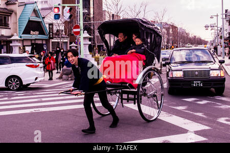 Familie Rikscha-fahrt in belebten Straße, rikscha Fahrer Kamera suchen, lächelnd, Kamakura, Japan Stockfoto