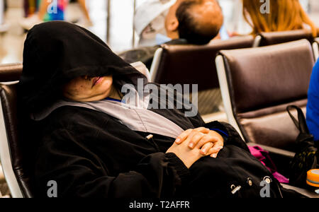 Frau schlafen auf Stuhl, Haube, Gesicht, am Flughafen Hong Kong, Hong Kong Stockfoto